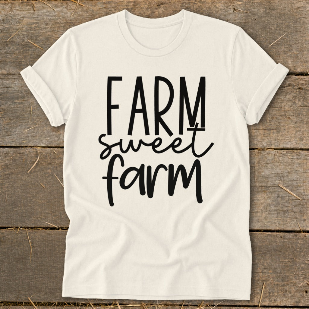 Cream t-shirt with black text "Farm sweet farm" on a wooden background.