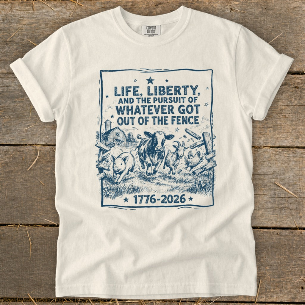 White t-shirt with navy graphic of farm animals escaping fence, text "Life, Liberty, and the pursuit of whatever got out of the fence".