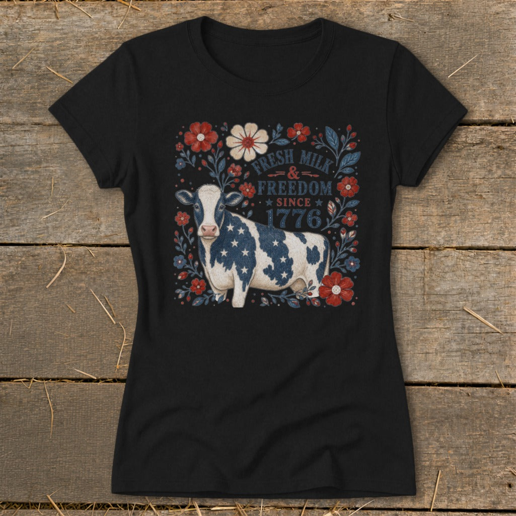 Black t-shirt with a cow design and text "Fresh Milk & Freedom Since 1776".