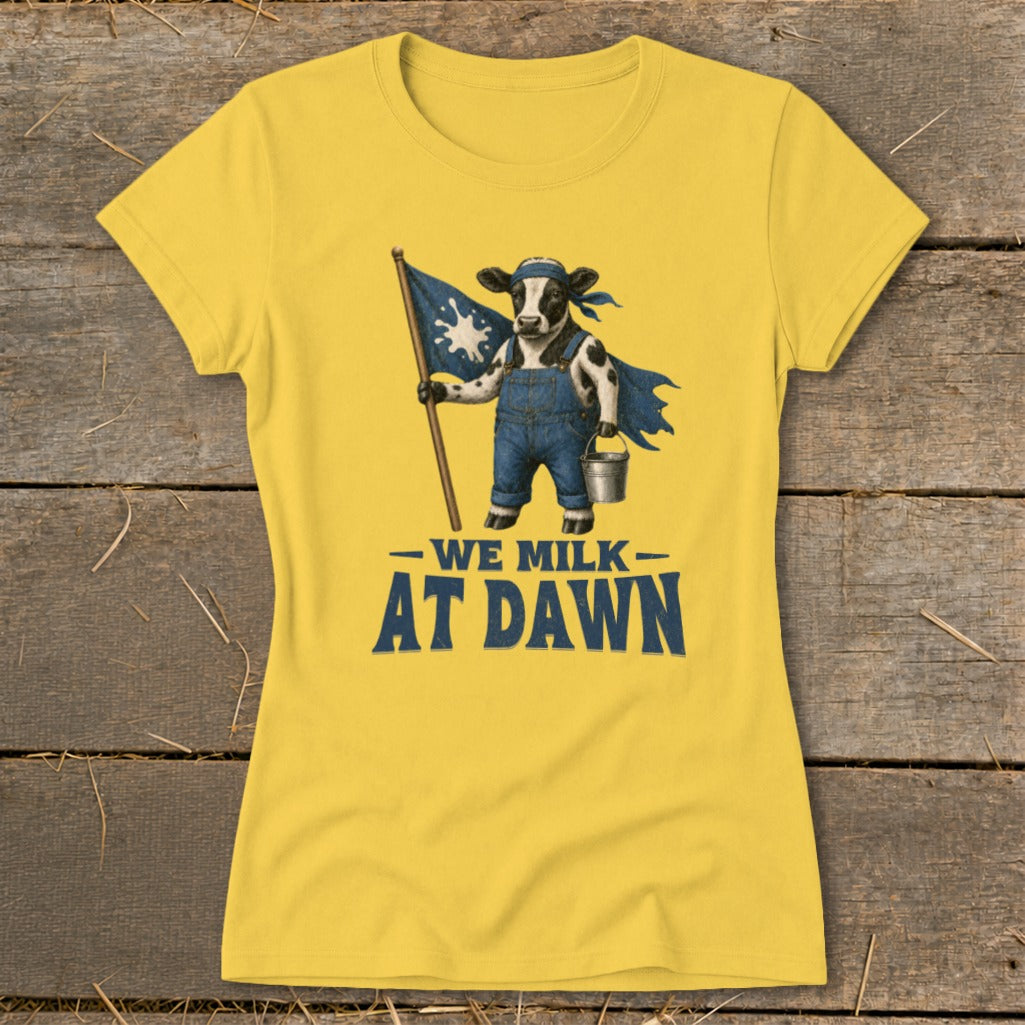 Yellow t-shirt with a cow in overalls holding a flag and bucket, text reads "We Milk At Dawn".