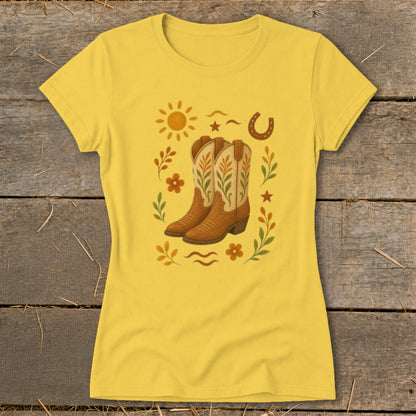 Yellow t-shirt with a graphic of cowboy boots, sun, horseshoe, and floral elements.