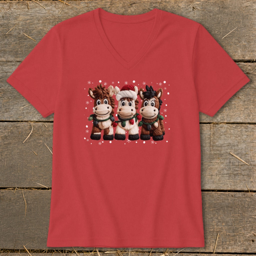 Three cartoon horses in festive attire with snowflakes on a red t-shirt.