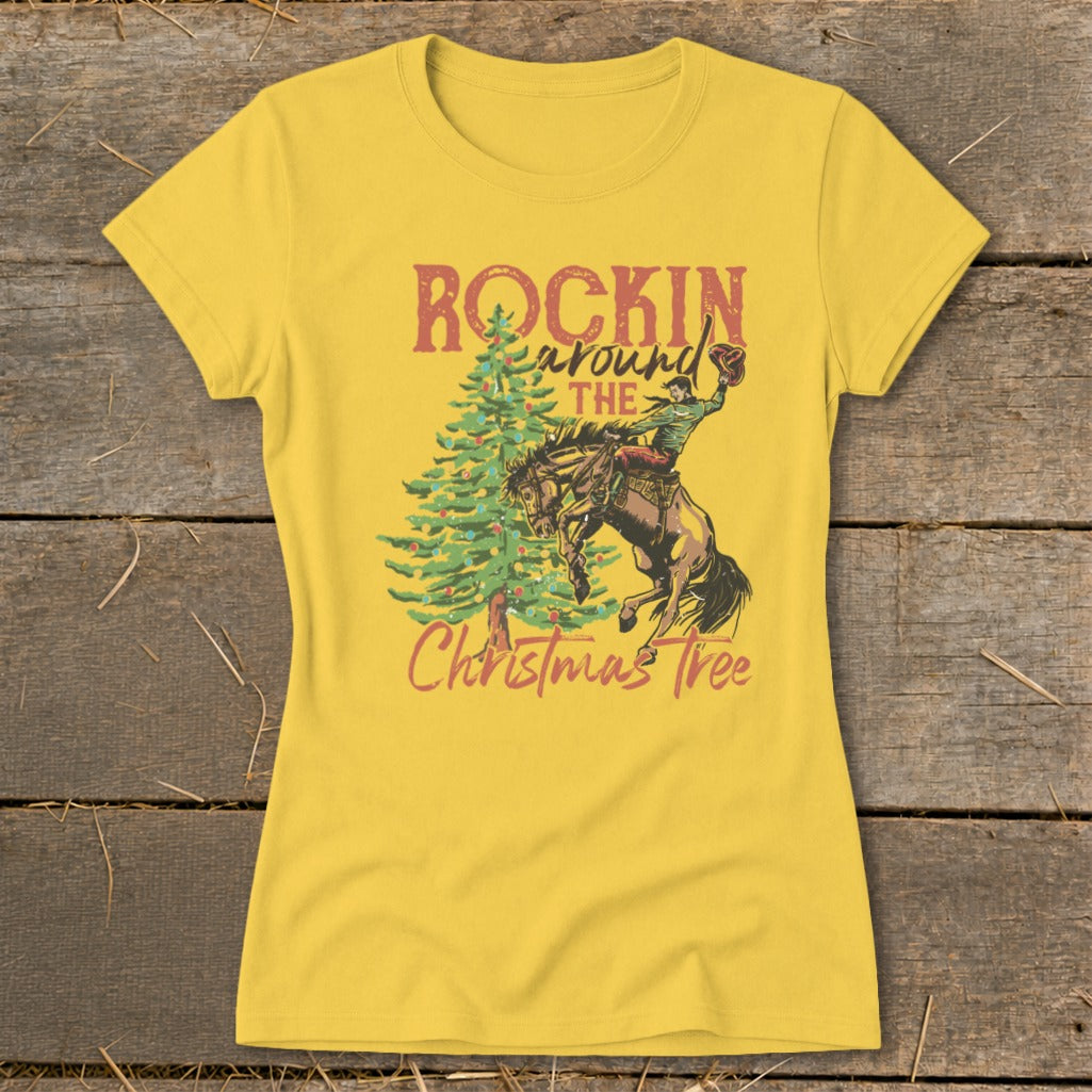 Yellow t-shirt with graphic of bucking bronco and cowboy next to Christmas tree, text "Rockin Around The Christmas Tree".