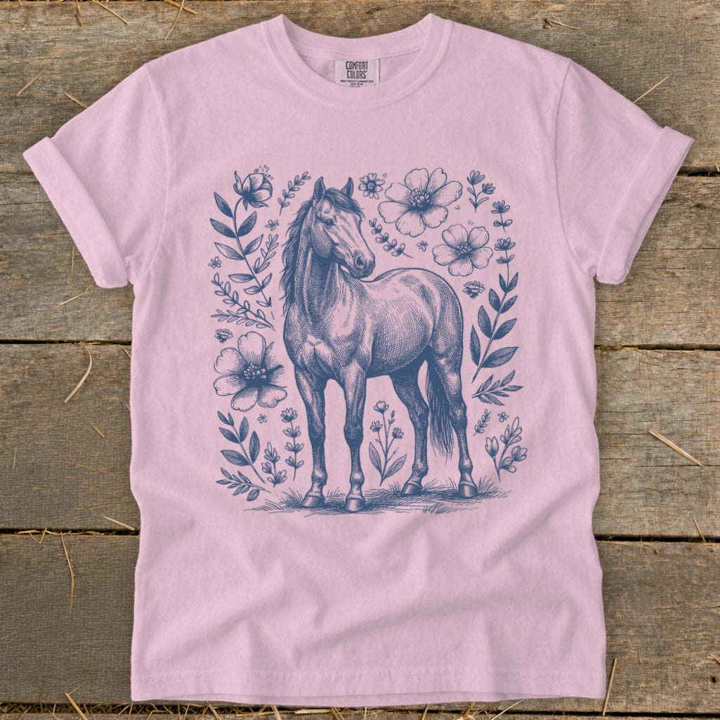 Pink t-shirt with navy blue sketch of a horse surrounded by flowers.