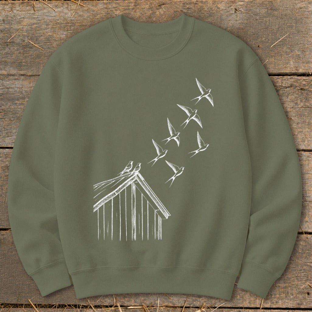 An olive green crewneck sweatshirt featuring a white sketch graphic of birds flying up from a birdhouse roof.