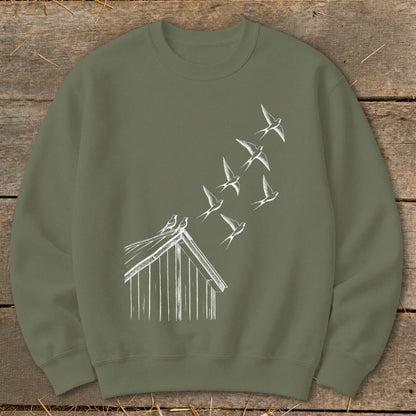 An olive green crewneck sweatshirt featuring a white sketch graphic of birds flying up from a birdhouse roof.