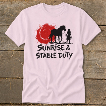 Pink t-shirt with silhouette of horse and rider against a red sun and the text "Sunrise & Stable Duty".