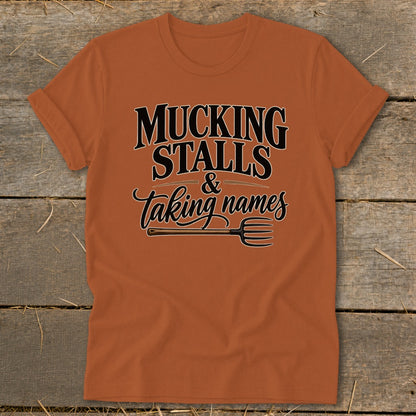 Orange t-shirt with "Mucking Stalls & Taking Names" text and pitchfork graphic.