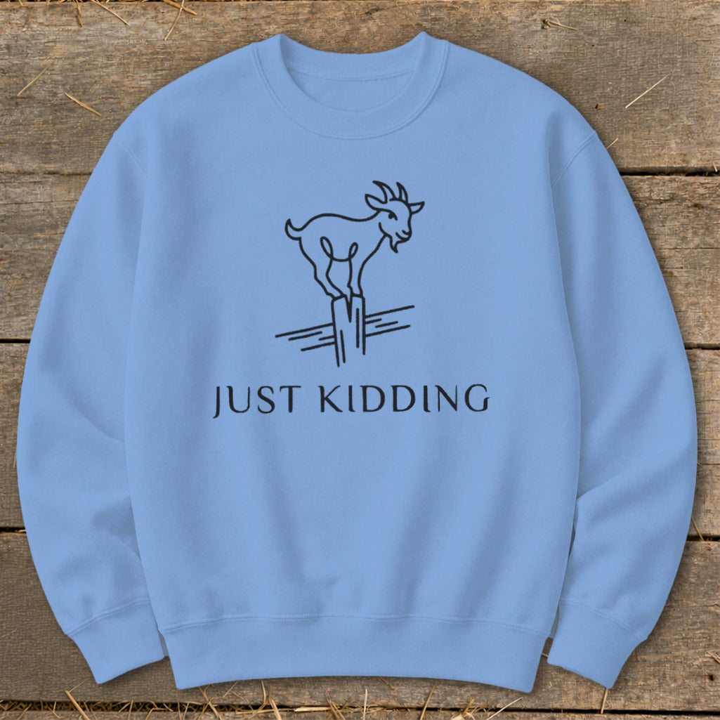 Light blue sweatshirt with black line drawing of a goat and text "JUST KIDDING".