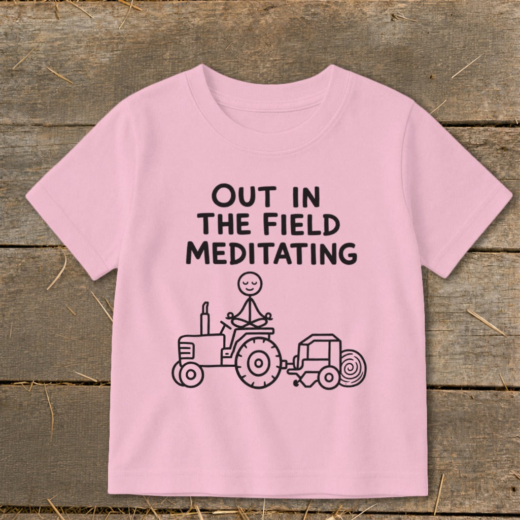Pink t-shirt with "OUT IN THE FIELD MEDITATING" text and a tractor graphic.