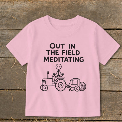 Pink t-shirt with "OUT IN THE FIELD MEDITATING" text and a tractor graphic.