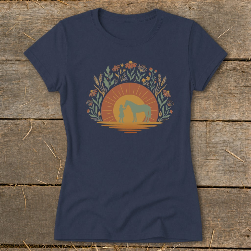 Graphic of a person and horse with a sunset and floral wreath.