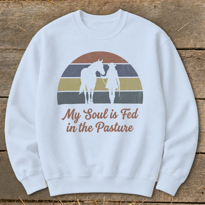 White sweatshirt with horse, person, and text "My Soul is Fed in the Pasture".