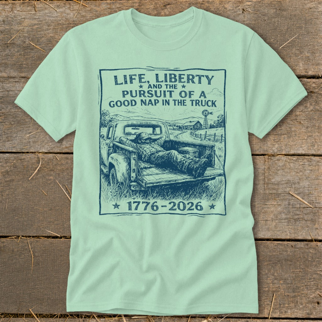 Pale green t-shirt with a sketch of a man napping in a truck bed, featuring text.