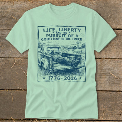 Pale green t-shirt with a sketch of a man napping in a truck bed, featuring text.