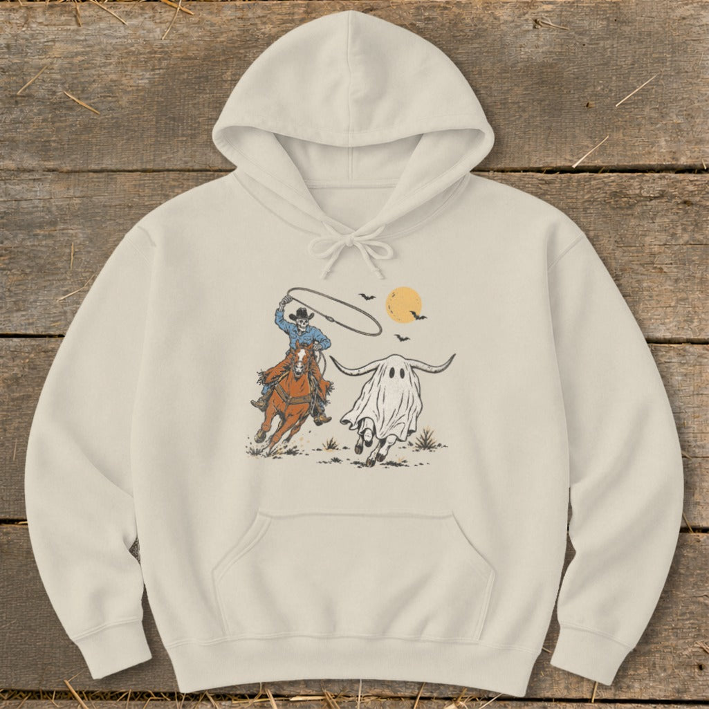 Skeleton cowboy on horseback lassoing a ghost steer under a harvest moon.