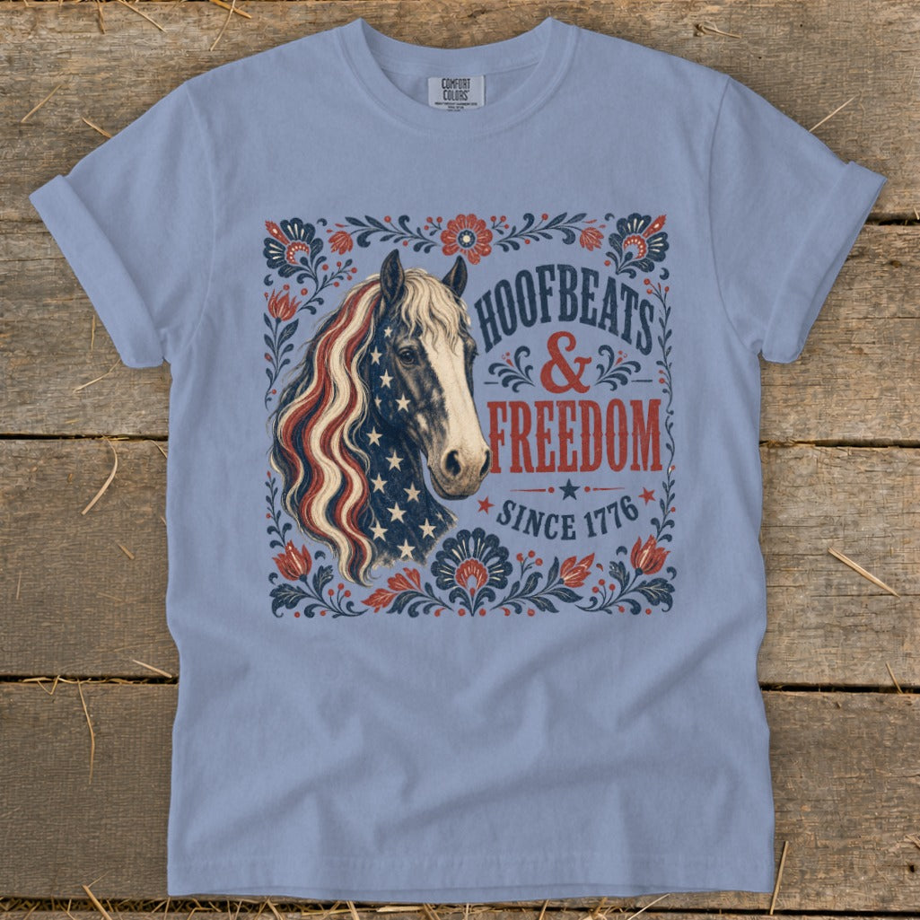 Light blue t-shirt with horse, American flag mane, and "Hoofbeats & Freedom Since 1776".
