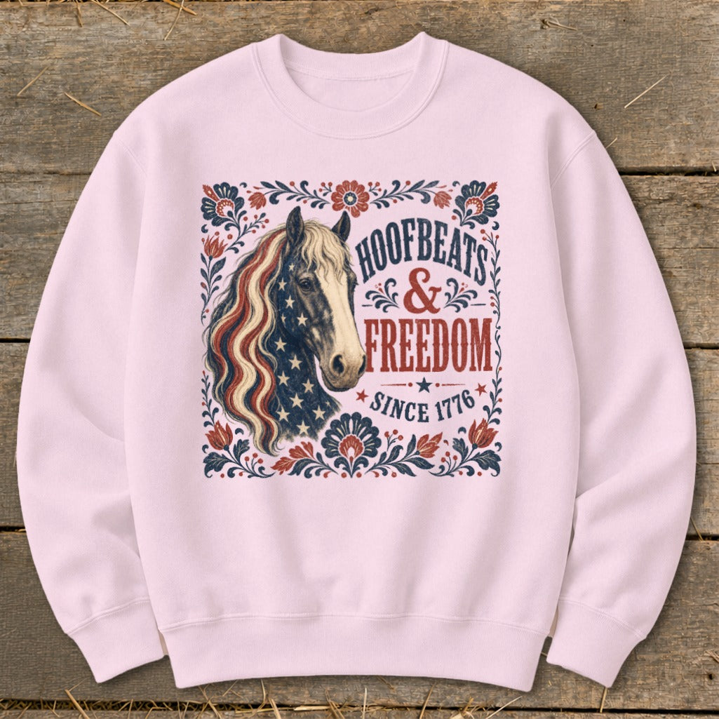 Light pink crewneck sweatshirt with horse and patriotic text "HOOFBEATS & FREEDOM SINCE 1776".
