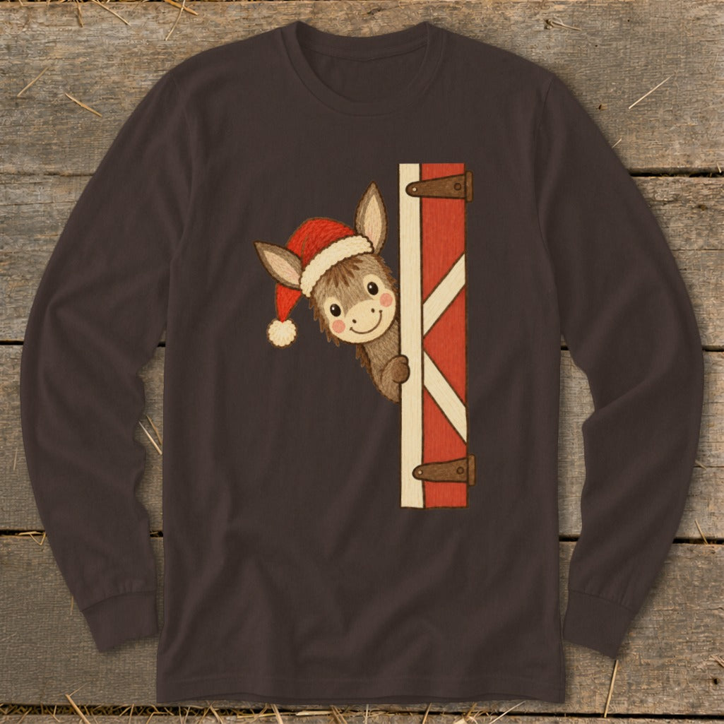 Donkey wearing Santa hat peeks around a red barn door on brown long-sleeve shirt.