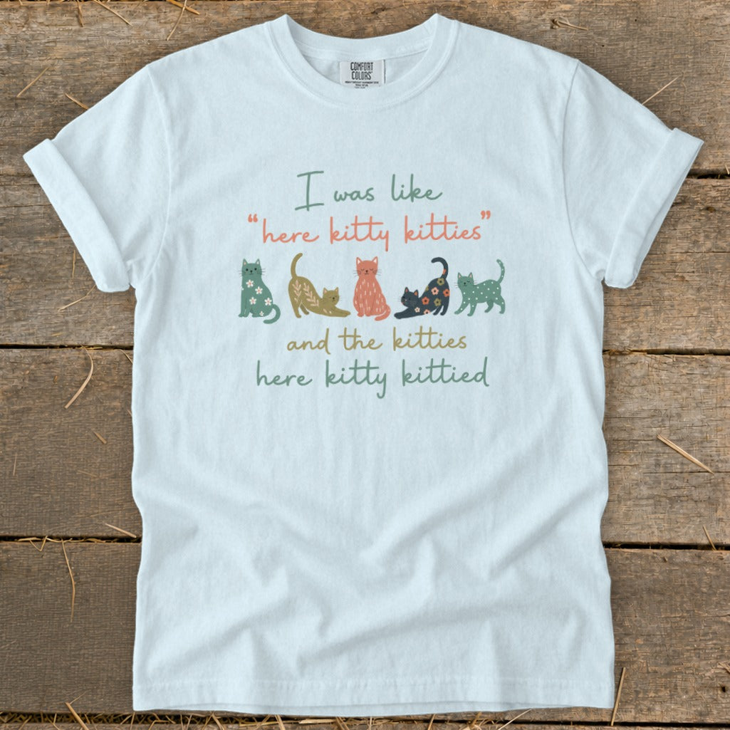 White t-shirt with "I was like 'here kitty kitties' and the kitties here kitty kittied" and cat illustrations.