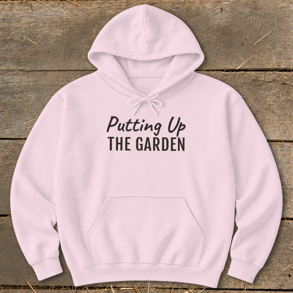 Pink hoodie with "Putting Up THE GARDEN" text in black lettering.