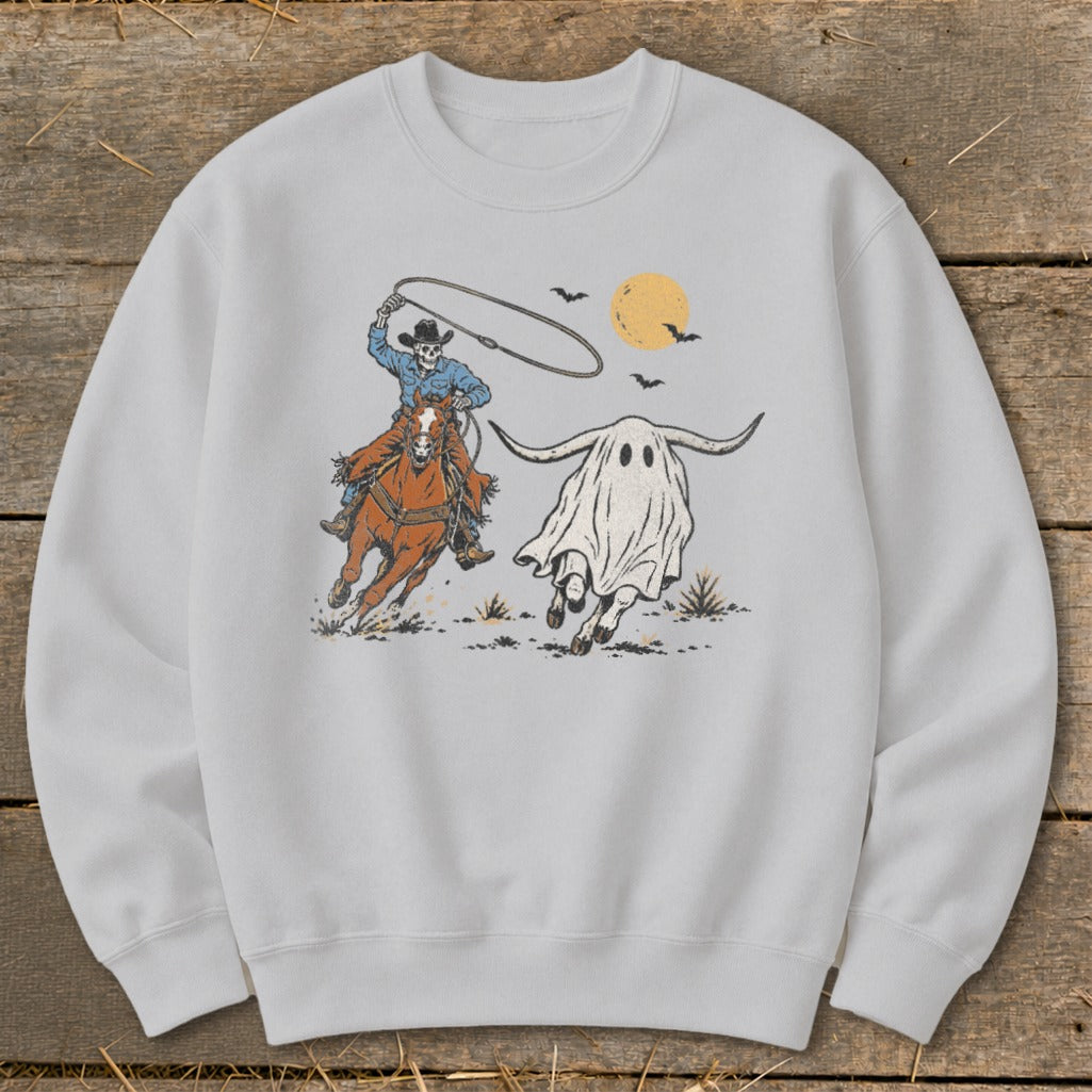 Skeleton cowboy on horseback lassoing a longhorn ghost under a full moon.