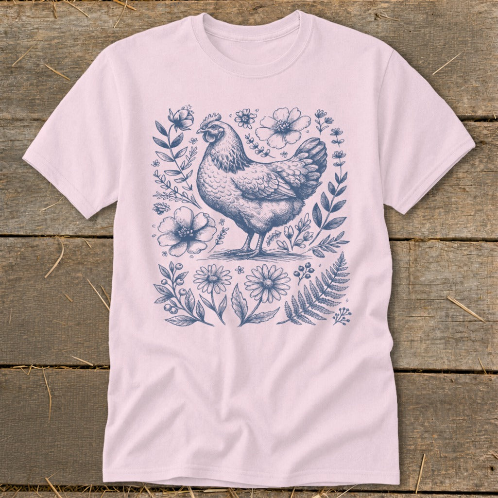 Pink t-shirt with a blue ink sketch of a chicken surrounded by flowers and ferns.