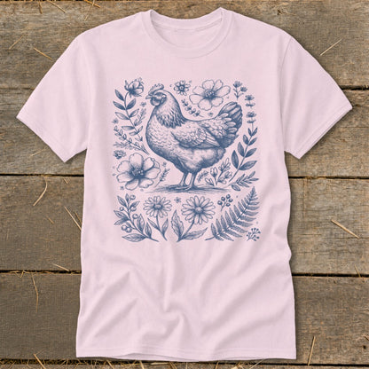 Pink t-shirt with a blue ink sketch of a chicken surrounded by flowers and ferns.