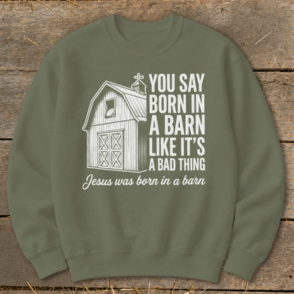 Olive green sweatshirt with white graphic of a barn and text about Jesus being born in a barn.