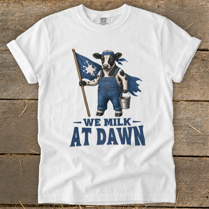 Cow in denim overalls holding a flag and milk bucket, text "WE MILK AT DAWN".