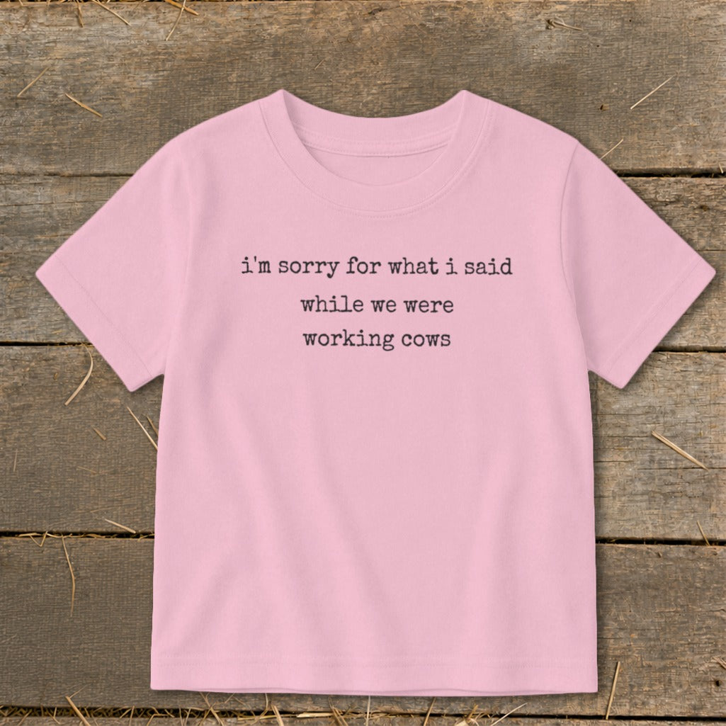 Pink t-shirt with black text reading "i'm sorry for what i said while we were working cows".