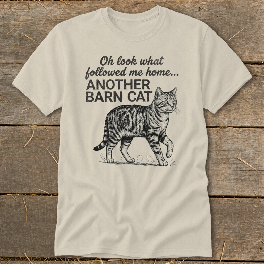 Cream t-shirt with black text and a tabby cat drawing saying "Oh look what followed me home... ANOTHER BARN CAT"