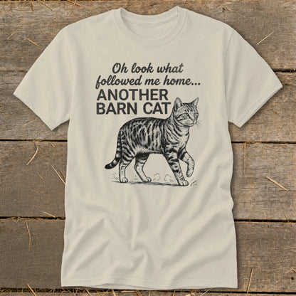 Cream t-shirt with black text and a tabby cat drawing saying "Oh look what followed me home... ANOTHER BARN CAT"