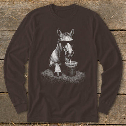 Horse wearing sunglasses, drinking from a straw in a cup, on a haystack.