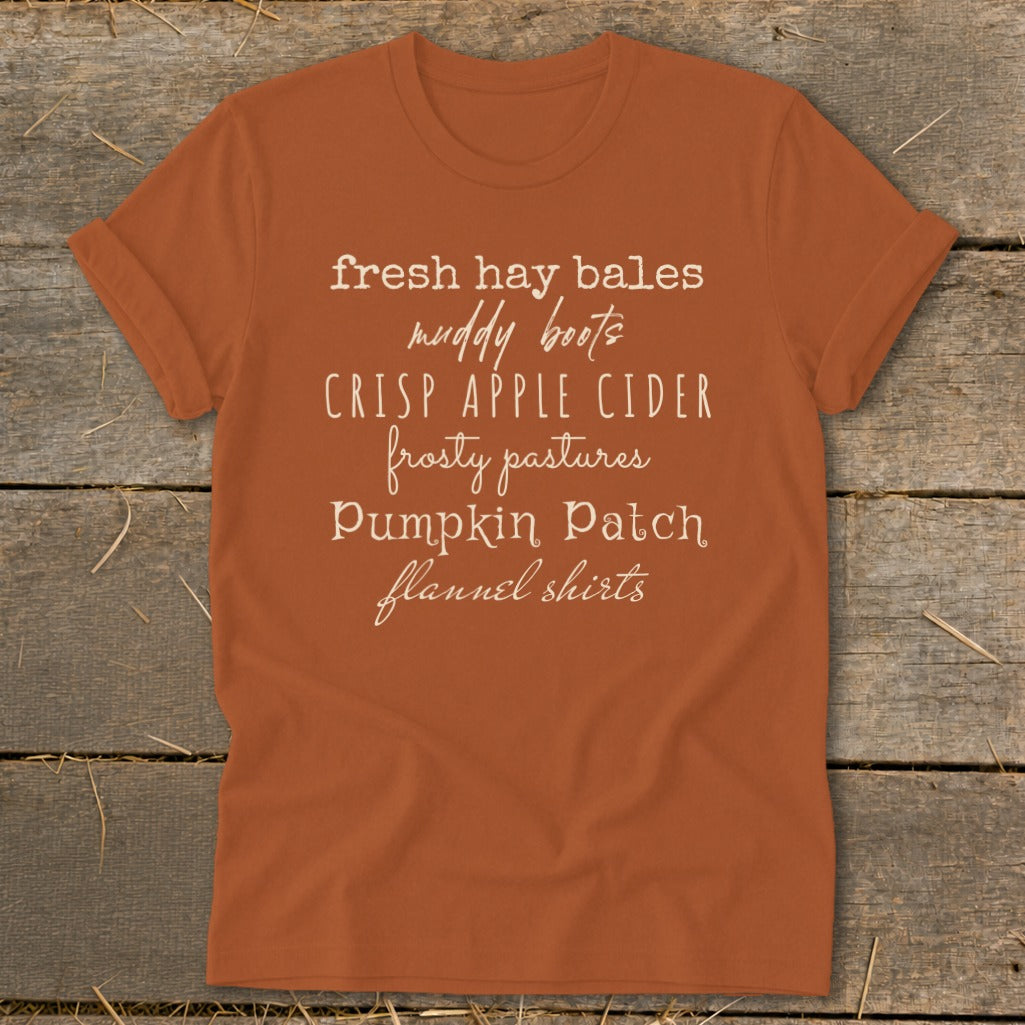 Orange t-shirt with text: fresh hay bales, muddy boots, crisp apple cider, frosty pastures, pumpkin patch, flannel shirts.