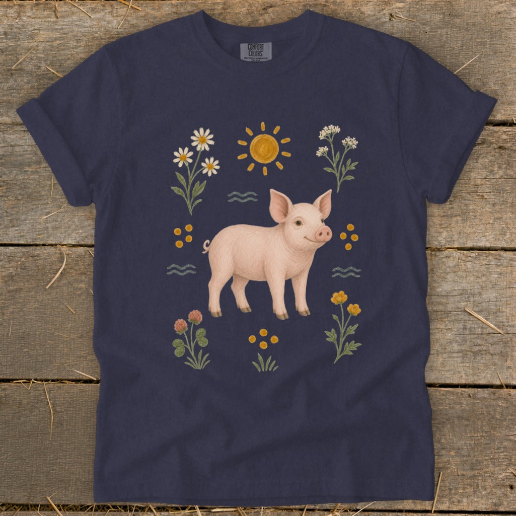 Navy t-shirt with a pink piglet surrounded by flowers, sun, and wavy lines.