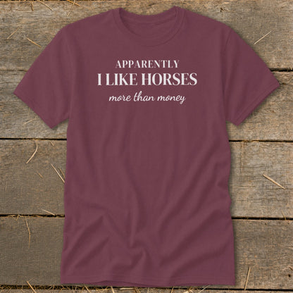 Maroon t-shirt with white text that reads "APPARENTLY I LIKE HORSES more than money".