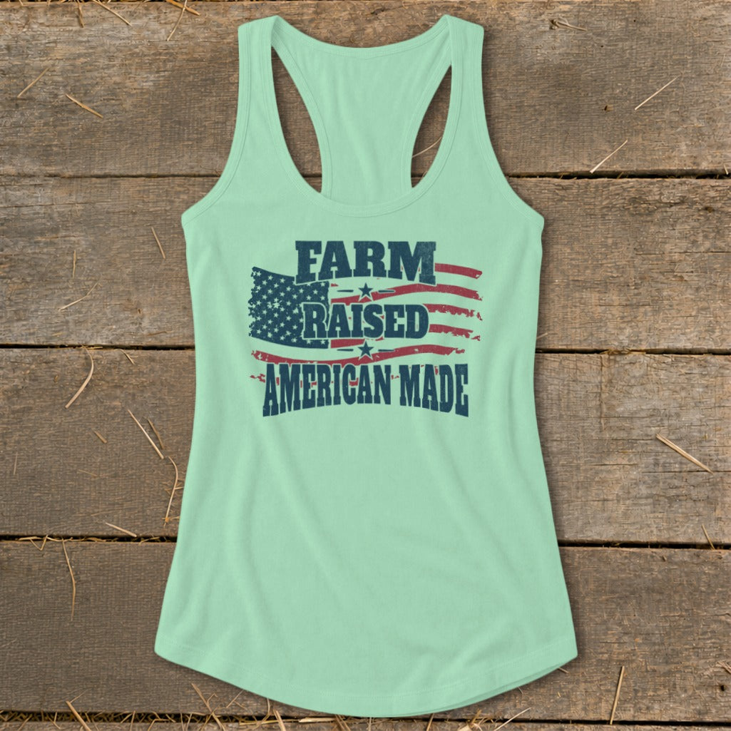 Light mint green racerback tank top with "FARM RAISED AMERICAN MADE" text over American flag graphic.