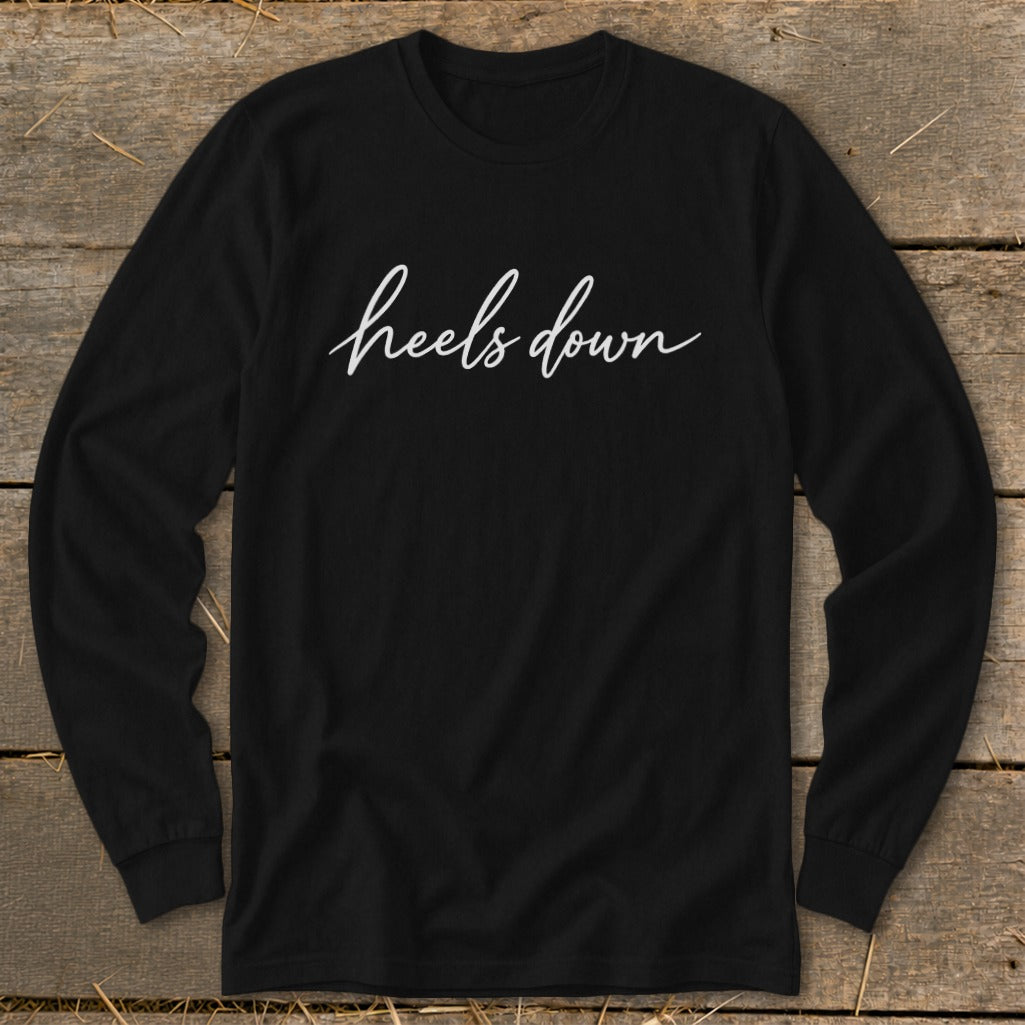 Black long-sleeve shirt with "heels down" in white cursive text.
