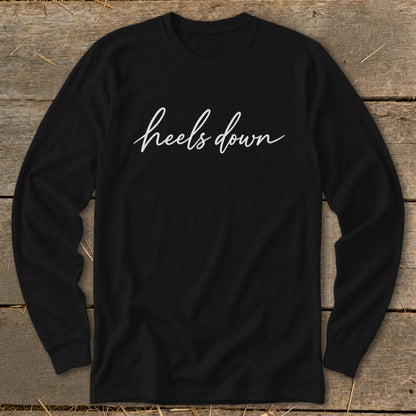 Black long-sleeve shirt with "heels down" in white cursive text.
