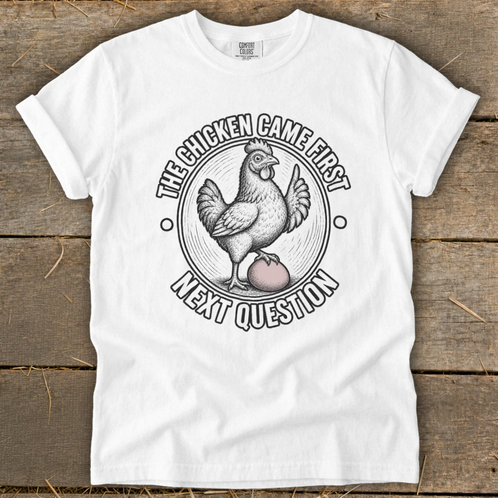 White t-shirt with chicken on egg graphic and text "The chicken came first, next question."
