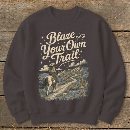 Dark grey sweatshirt with a graphic of a woman on horseback on a desert trail, reading "Blaze Your Own Trail".