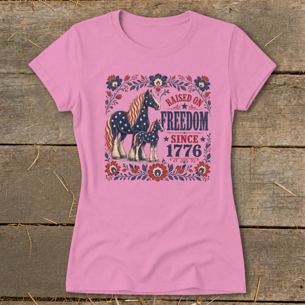 Pink t-shirt with "Raised on Freedom Since 1776" and patriotic horses graphic.