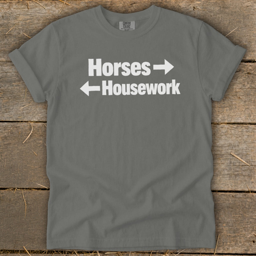 A dark gray t-shirt with white text reading Horses with a right arrow and Housework with a left arrow.