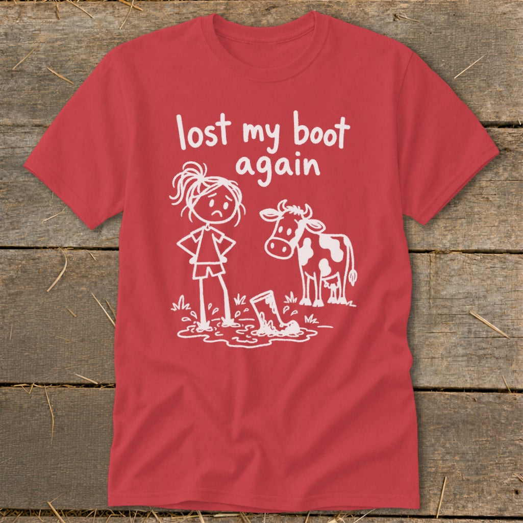 Red t-shirt featuring white graphic of a sad girl and cow next to a muddy boot, with text reading lost my boot again.