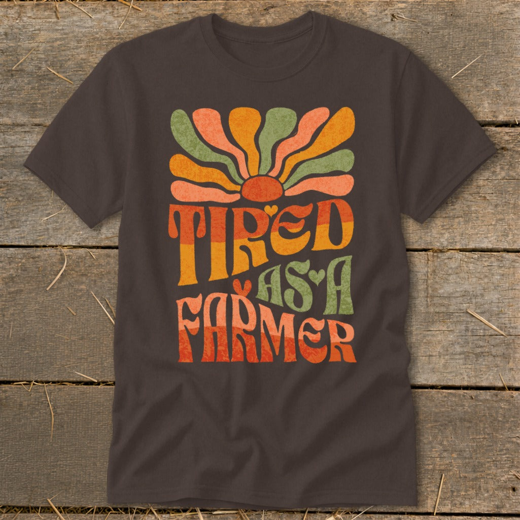 Brown t-shirt with retro text "Tired As A Farmer" and colorful sun design.