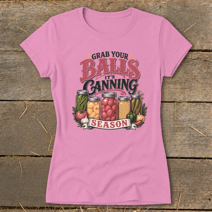 Pink t-shirt with "Grab Your Balls It's Canning Season" text and jars of preserved vegetables.