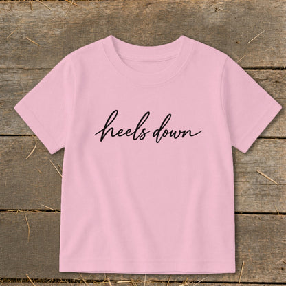 Pink t-shirt with black cursive text "heels down"