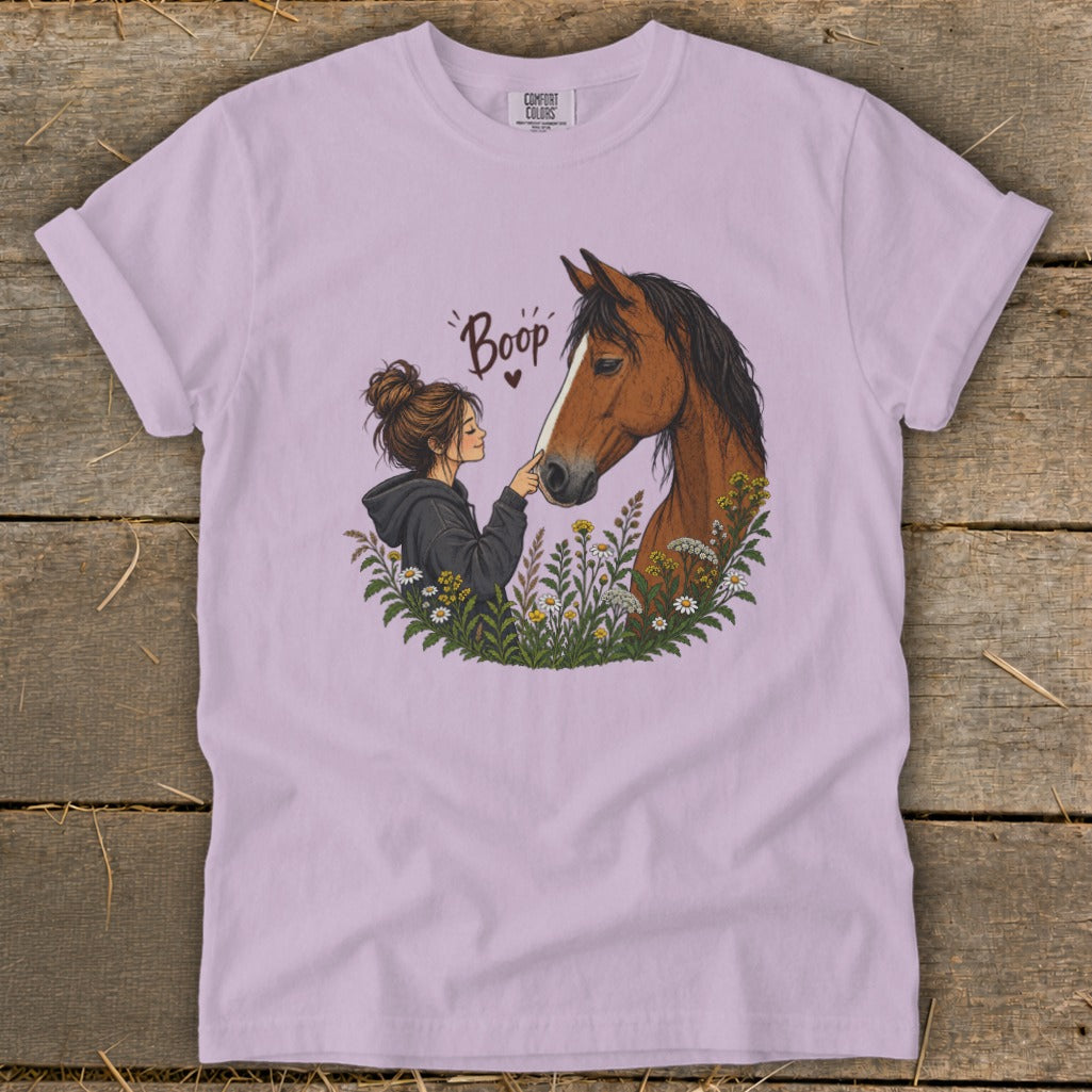 Illustration of a girl booping a horse's nose surrounded by flowers on a lilac t-shirt.