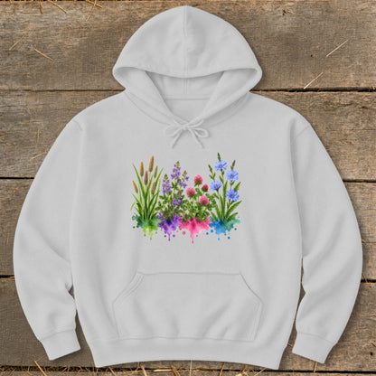 A light gray hooded sweatshirt with a watercolor print of wildflowers on the chest, laid flat on a wooden surface.